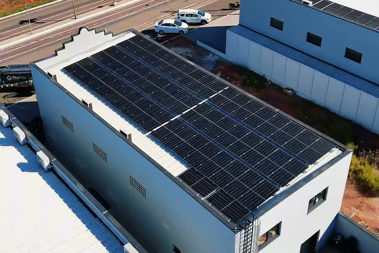 Vista aérea de prédio comercial à beira de avenida, com a cobertura inteira tomada por módulos fotovoltaicos